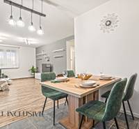 Interiér rodinného domu s podlahou s dřevěným dekorem, jídelní stůl a zelené židle.