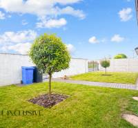 Zahrada rodinného domu v Gabčíkově s trávníkem, stromem a chodníkem vedle plotu.