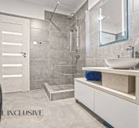 Koupelna se sprchou, umyvadlem na dřevěné desce a pračkou v rodinném domě.