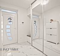 Interiér rodinného domu s bílými skříněmi, zrcadlem a podlahou s mramorovým dekorem.