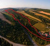 Letecký pohled na zemědělské a lesní pozemky u Rokycan obklopené zelení a silnicí.