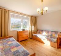 Pokoj v rodinném domě s postelemi, dřevěným dekorem a pestrými přikrývkami.