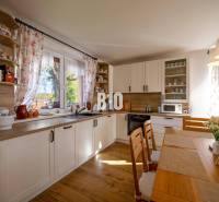 Kuchyně v rodinném domě s podlahou s dřevěným dekorem a světlým nábytkem.