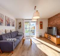 Obývací pokoj v rodinném domě s pohovkou, cihlovou stěnou a podlahou s dřevěným dekorem.