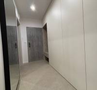 Vstupní chodba 2pokojového bytu s bílými skříňkami a zrcadlem na stěně.