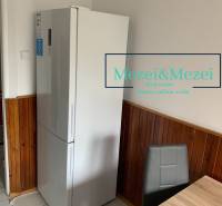 Kuchyně v 2pokojovém bytě, lednice, dřevěný obklad, šedá židle, jídelní stůl.