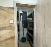 Malý sklad ve 3-pokojovém bytě s regály a kbelíkem.