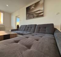 Světlý obývací pokoj s pohodlnou sedačkou a velkým oknem v 3-pokojovém bytě.