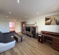 Obývací pokoj v 3-pokojovém bytě s podlahou s dřevěným dekorem a pohodlnou sedací soupravou.