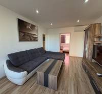 Obývací pokoj v 3-pokojovém bytě s rohovou sedačkou a podlahou s dřevěným dekorem.