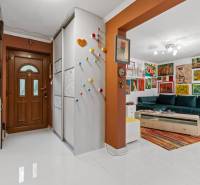 Chodba v rodinném domě s pestrou výzdobou a barevným obývacím pokojem.