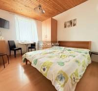 Hotelový pokoj s dvoulůžkem, televizí, stolem a podlahou s dřevěným dekorem.