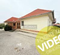 Exteriér hotelu a penzionu v Podhájské s terasou, červenou střechou a zelenými keři.