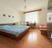 Pokoj s manželskou postelí, jednolůžkem, skříní a podlahou s dřevěným dekorem v hotelech a penzionech.