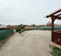 Exteriér v Podhájské vedle hotelů a penzionů, štěrkem pokrytý dvůr a přístřešek.