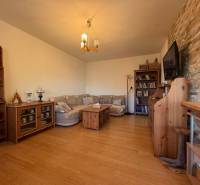 Obývací pokoj s pohovkou, podlaha s dřevěným dekorem, knihovna a televize na stěně.