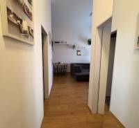 Chodba v 2-pokojovém bytě s podlahou s dřevěným dekorem a dekoracemi na stěnách.