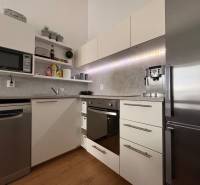 Kuchyně v 2pokojovém bytě s podlahou s dřevěným dekorem a moderními spotřebiči.