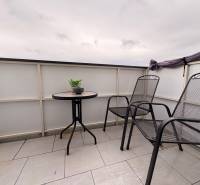 Balkon 2-pokojového bytu v Komárně se dvěma židlemi a stolkem na dlažbě.