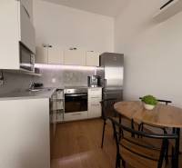 Kuchyně v 2pokojovém bytě s podlahou s dřevěným dekorem a jídelním stolem.