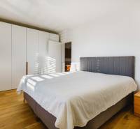 Ložnice s velkou postelí, šatní skříní a podlahou s dřevěným dekorem v rodinném domě.