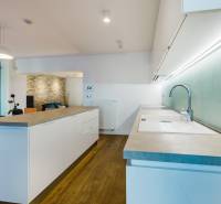 Kuchyně s ostrůvkem, cihlovou stěnou a podlahou s dřevěným dekorem v rodinném domě.