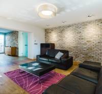 Obývací pokoj v rodinném domě s cihlovou stěnou a podlahou s dřevěným dekorem.