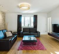 Obývací pokoj s koženou sedačkou, cihlovou stěnou a podlahou s dřevěným dekorem v rodinném domě.