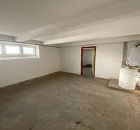 Prázdná místnost v rodinném domě s okny a kotlem.