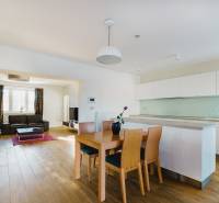 Kuchyň a obývací pokoj v rodinném domě s podlahou s dřevěným dekorem a světlým nábytkem.