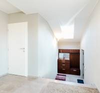 Interiér rodinného domu s dlažbou a bílými stěnami, schodiště a světlík.