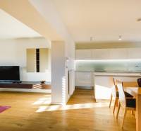 Rodinný dům s otevřenou kuchyní, dřevěným dekorem podlahy a jídelním stolem.