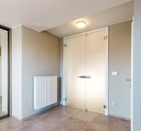 Vstupní hala v rodinném domě s minimalistickým designem, zrcadlem a světlými stěnami.