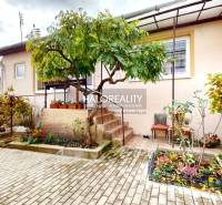 Rodinný dům v Lučenci s upraveným dvorem, květinovou zahradou a cihlovou dlažbou.