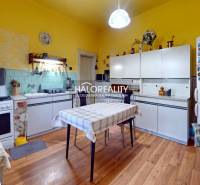 Jasná kuchyně v rodinném domě s bílými skříňkami a podlahou s dřevěným dekorem.