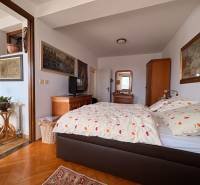 Pokoj v 5 a více pokojovém bytě s postelí, uměním na stěnách a podlahou s dřevěným dekorem.