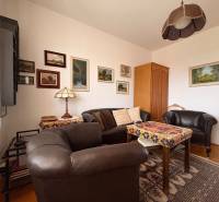 Pokoj pětipokojového a většího bytu s koženým nábytkem a podlahou s dřevěným dekorem.