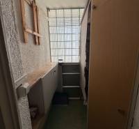 Úložný prostor v 3-pokojovém bytě s regály a prosklenou stěnou.