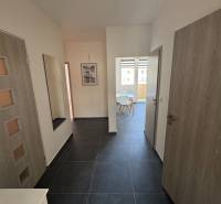 Vstupní chodba v 3pokojovém bytě s tmavou podlahou a světlými stěnami.