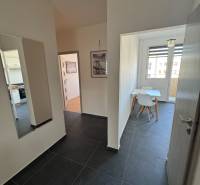 Chodba s tmavou dlažbou a jídelnou v 3-pokojovém bytě.