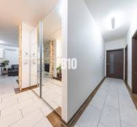 Chodba rodinného domu s dlažbou a zrcadlovou stěnou.