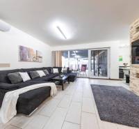 Obývací pokoj rodinného domu s pohovkou, krbem a posuvnými dveřmi na terasu.