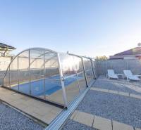 Zahrada rodinného domu v Mostě u Bratislavy s bazénem a lehátky.