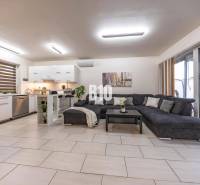 Světlý obývací pokoj v rodinném domě s kuchyní a velkou pohovkou.