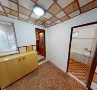 Interiér v rodinném domě s podlahou s dřevěným dekorem, skříňkou a vstupem do koupelny.