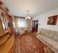 Obývací pokoj v rodinném domě s klasickou obývací stěnou a kobercem.