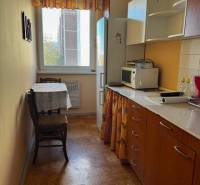 Kuchyně v 3-pokojovém bytě s podlahou s dřevěným dekorem a nábytkem v teplých barvách.