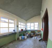 Interiér rodinného domu se starými okny a podlahou z betonu.