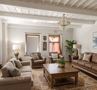 Obývací pokoj v rodinném domě s koženou sedačkou, podlahou s dřevěným dekorem a kobercem.