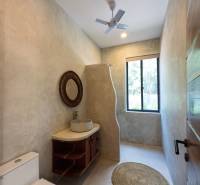 Koupelna s umyvadlem, kulatým kobercem a ventilátorem. Stavba domů.